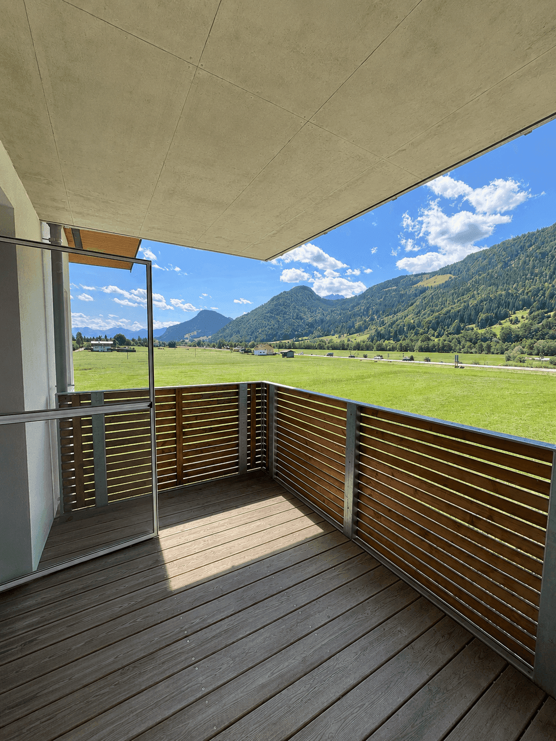 Privater Balkon mit Holzboden und Lattenzaun, bietet einen schönen Blick ins Grüne.