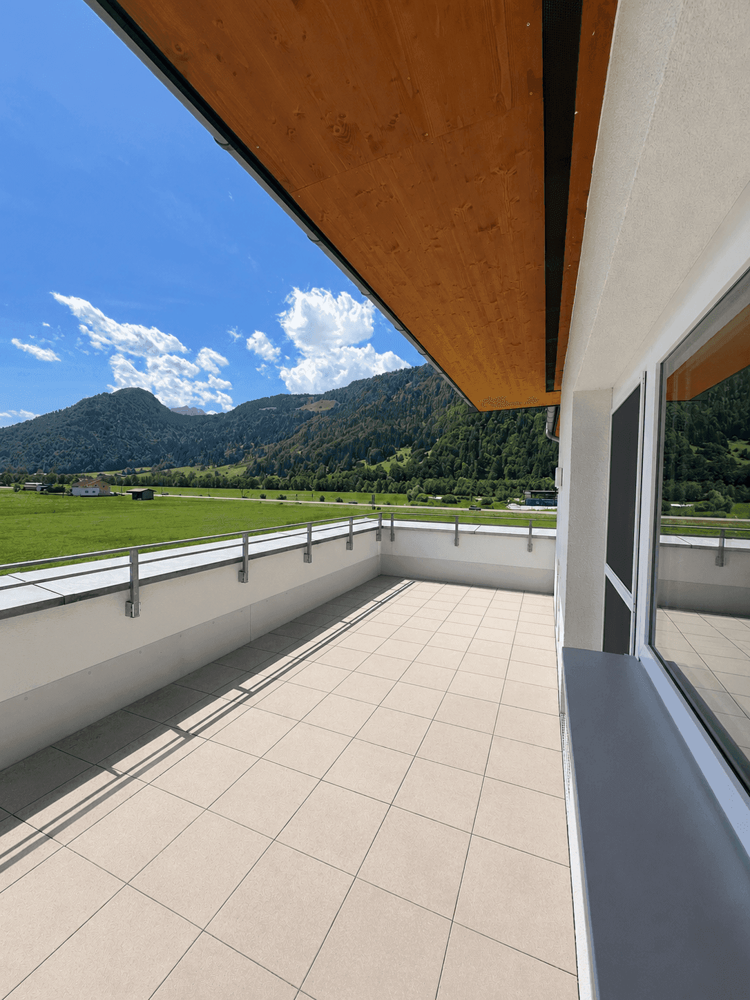 Sonniger Terrassenbereich mit moderner Überdachung und Panoramablick auf die Berge.