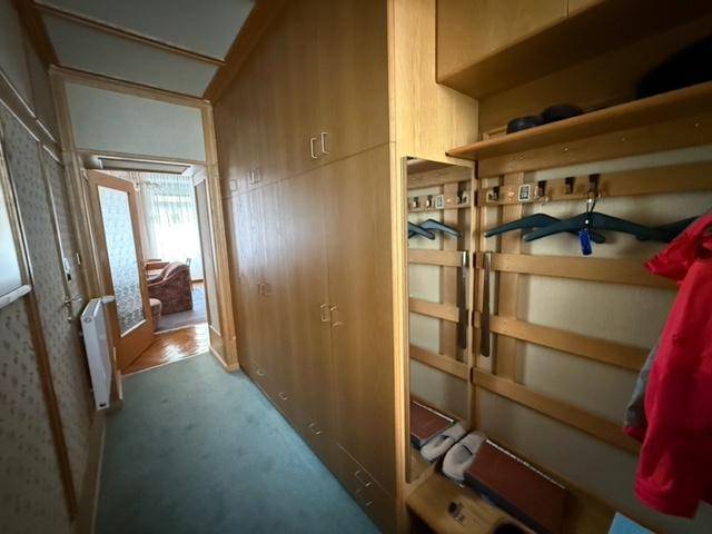 Flur mit Holzvertäfelung, integrierten Schränken und einem Garderobenbereich mit Spiegel.
