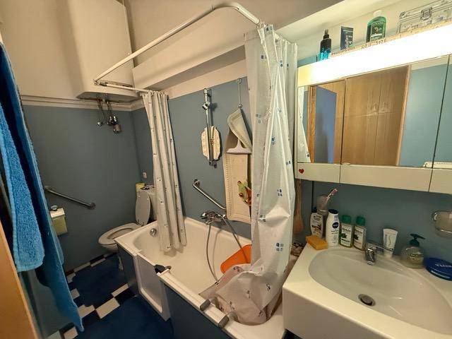 Badezimmer mit Badewanne, Duschvorhang und einem Waschbecken mit Spiegelschrank.
