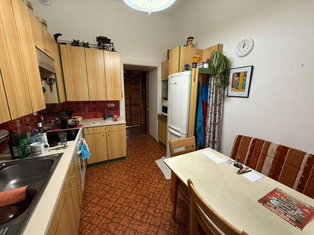 Küche mit Essbereich, Holzschränken und einem Kühlschrank, der in eine Nische passt.