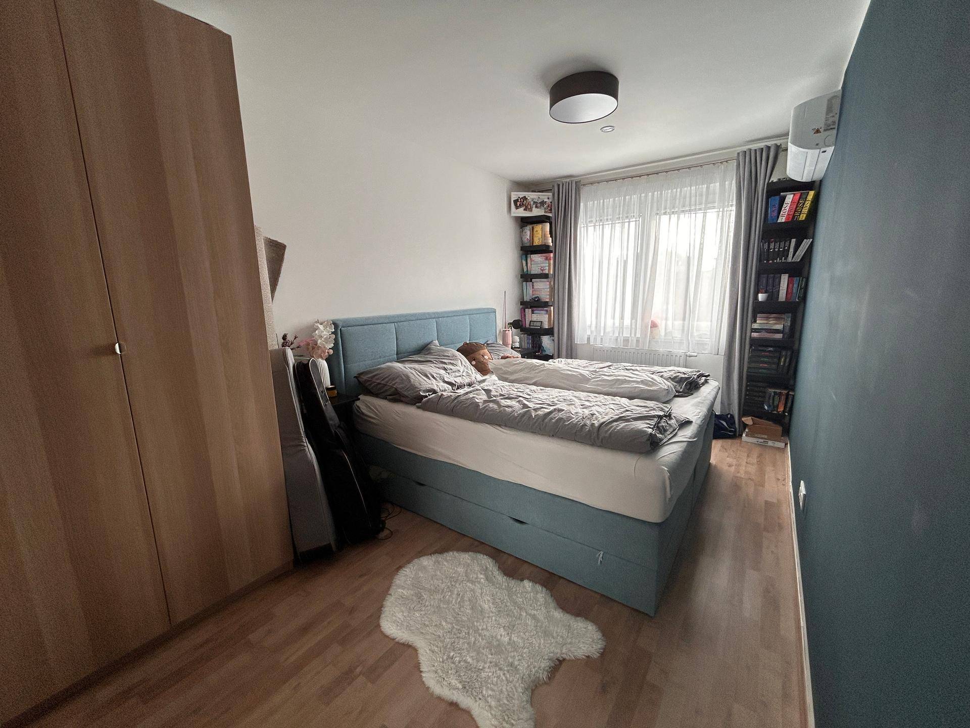 Schlafzimmer mit Doppelbett, großem Kleiderschrank und Fenster für viel Tageslicht.