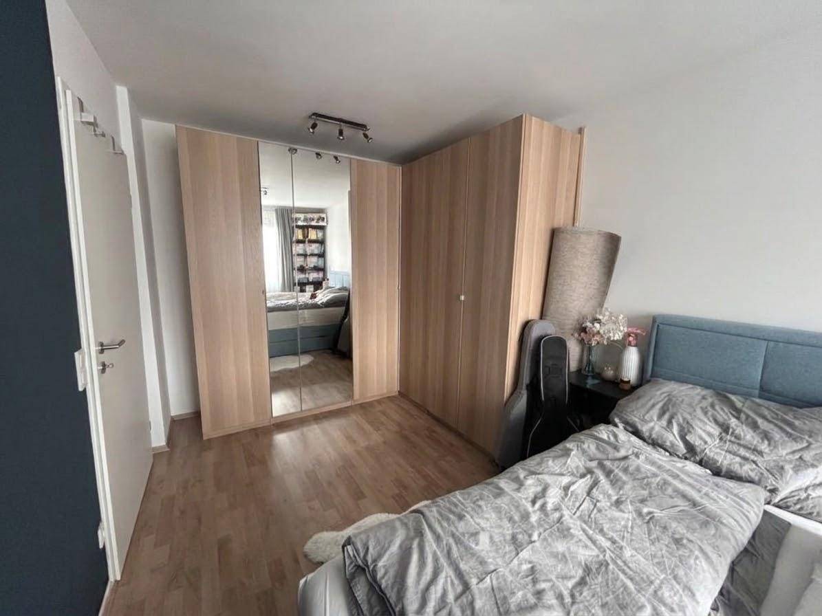 Schlafzimmer mit großem Bett, Holzschrank und Parkettboden, bietet viel Stauraum.