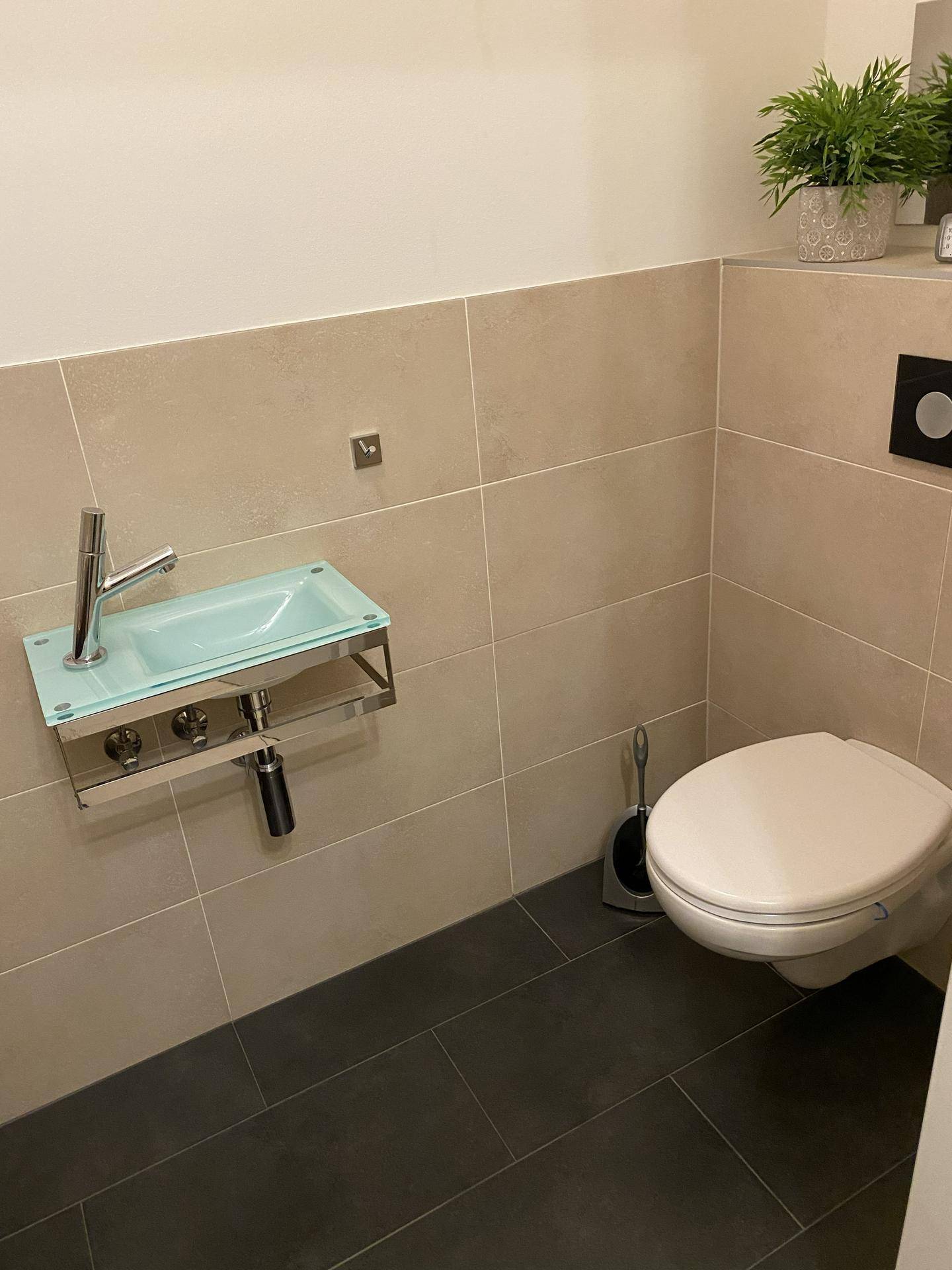 Gäste-WC mit wandhängender Toilette und kleinem, modernem Waschbecken.