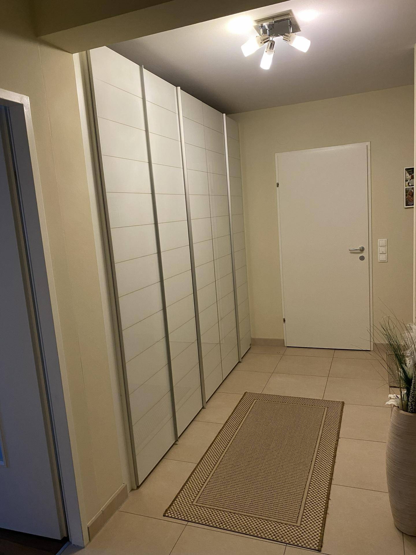Geräumiger Flur mit großen Einbauschränken, Fliesenboden und heller Beleuchtung.