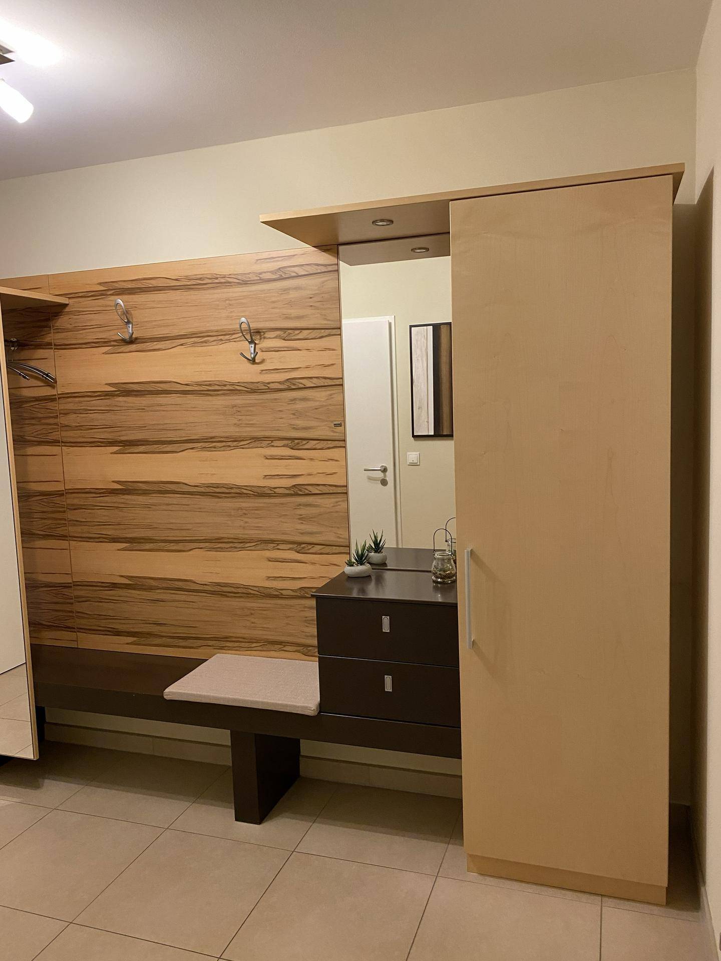 Moderner Flur mit Holzpaneelen, Spiegel, Garderobe und integriertem Schrank.