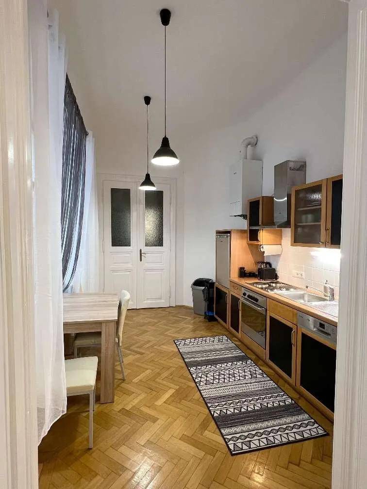 Helle Küche mit Holzschränken, integrierten Geräten und einem Esstisch am Fenster für gemeinsame Mahlzeiten.