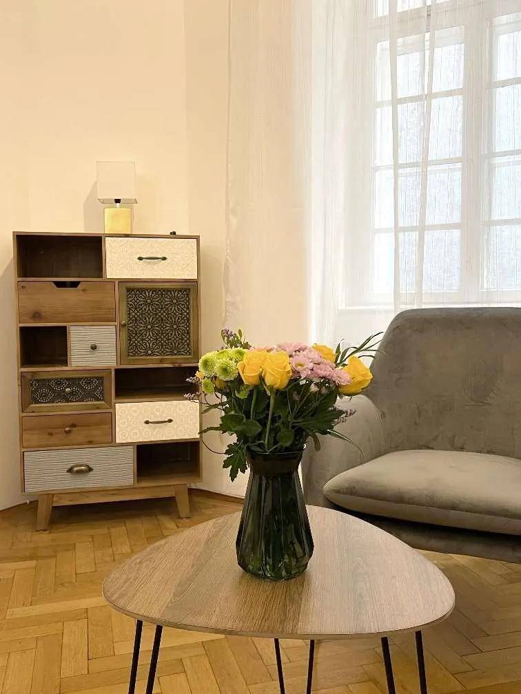 Detailansicht des Wohnzimmers mit einem bunten Blumenstrauß auf einem modernen Couchtisch neben einem Sessel.