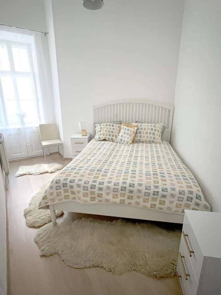 Gemütliches Schlafzimmer mit Doppelbett, hellen Wänden und weichen Teppichen auf dem Fischgrätparkettboden.