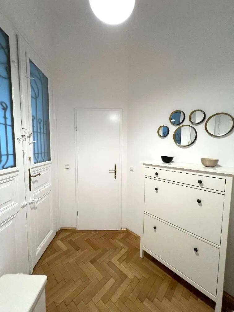 Freundlicher Flur mit Fischgrätparkett und einer weißen Schuhkommode, die den Raum organisiert und hell hält.
