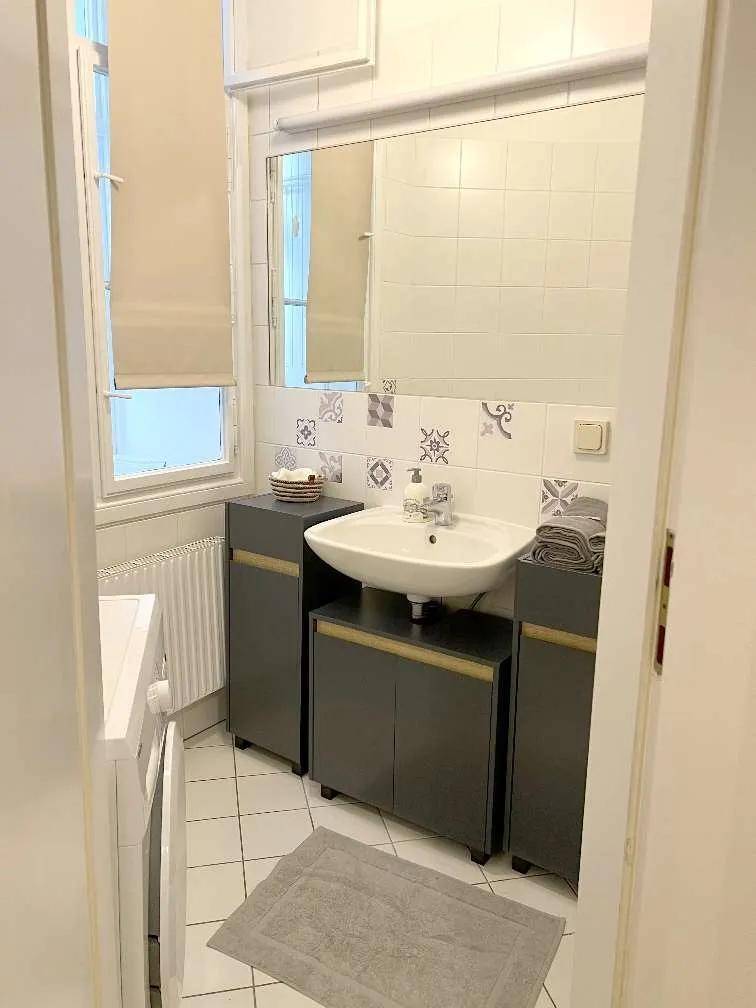 Funktionales Badezimmer mit Waschbecken, Spiegelschrank und Fliesenboden, inklusive einer Waschmaschine.