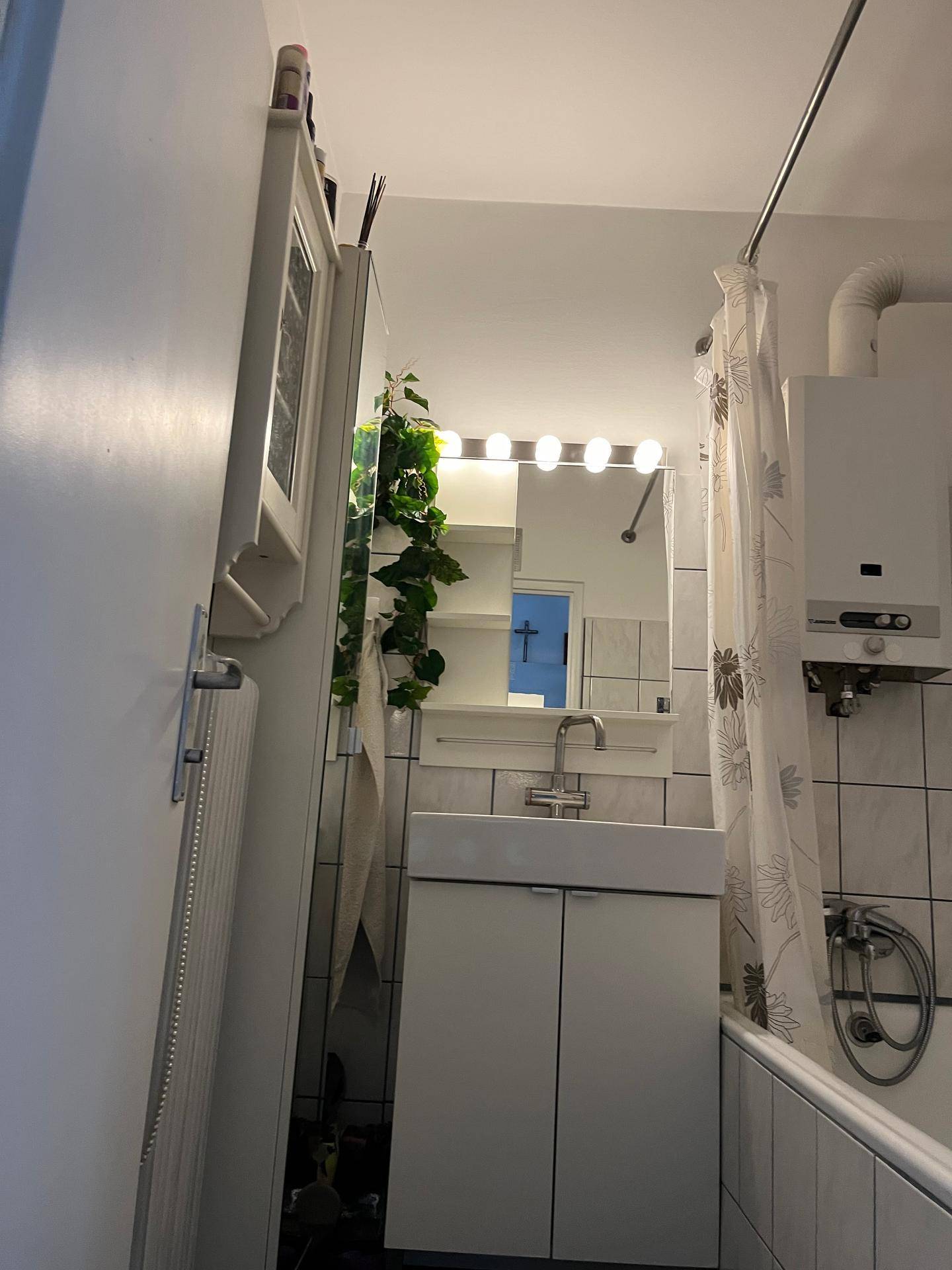 Kleines Badezimmer mit Badewanne, Waschbecken und Spiegel, ausgestattet mit einem Gasboiler.