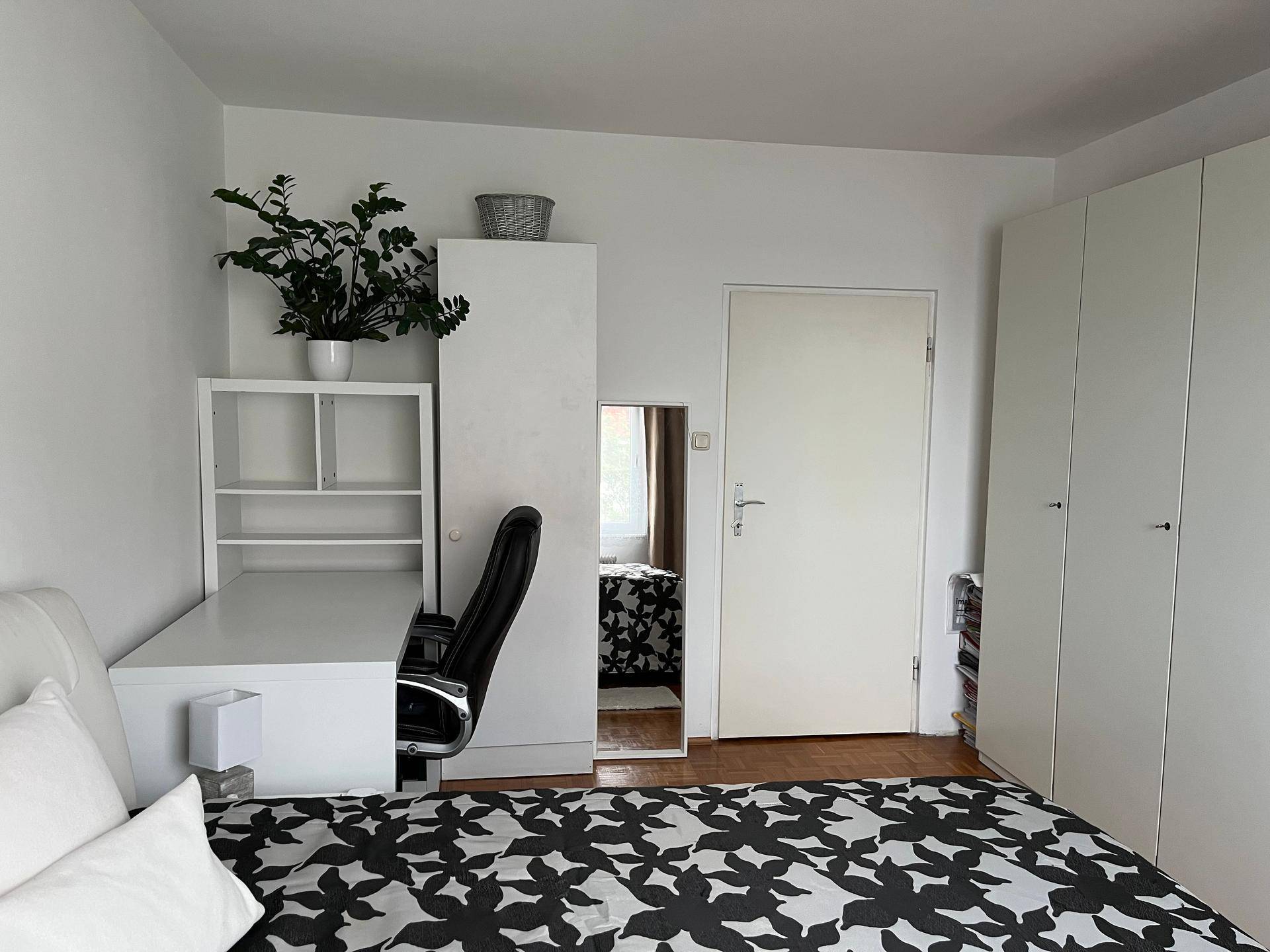 Schlafzimmer mit Schreibtisch, Kleiderschrank und Parkettboden, ideal als Arbeits- und Schlafbereich.