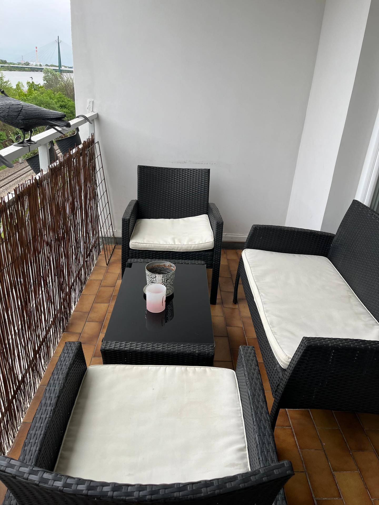 Gemütlicher Balkon mit Rattanmöbeln und Sichtschutz, ideal für entspannte Stunden im Freien.