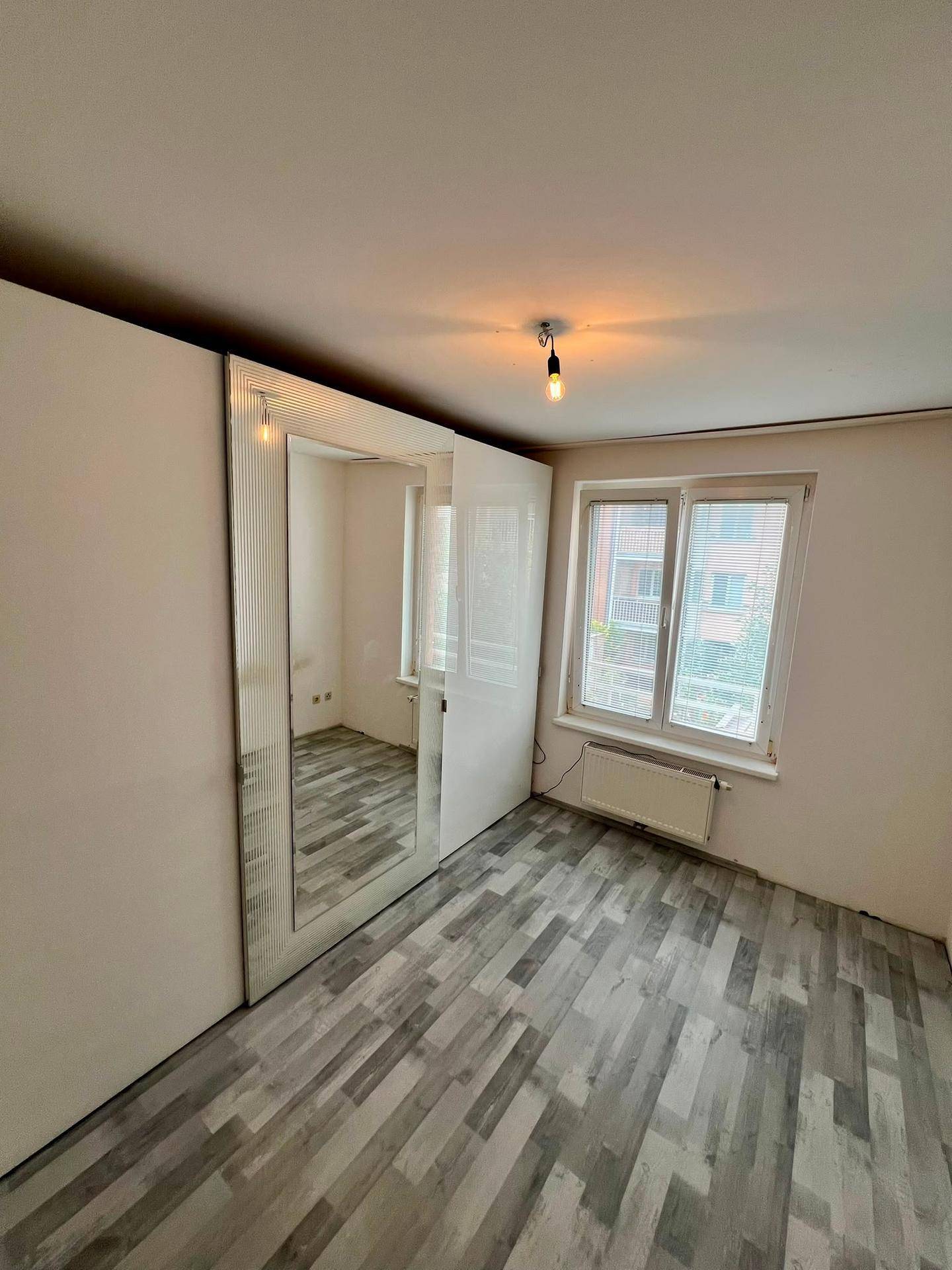 Schlafzimmer mit Laminatboden und großem Spiegelschrank, hell und funktional eingerichtet.