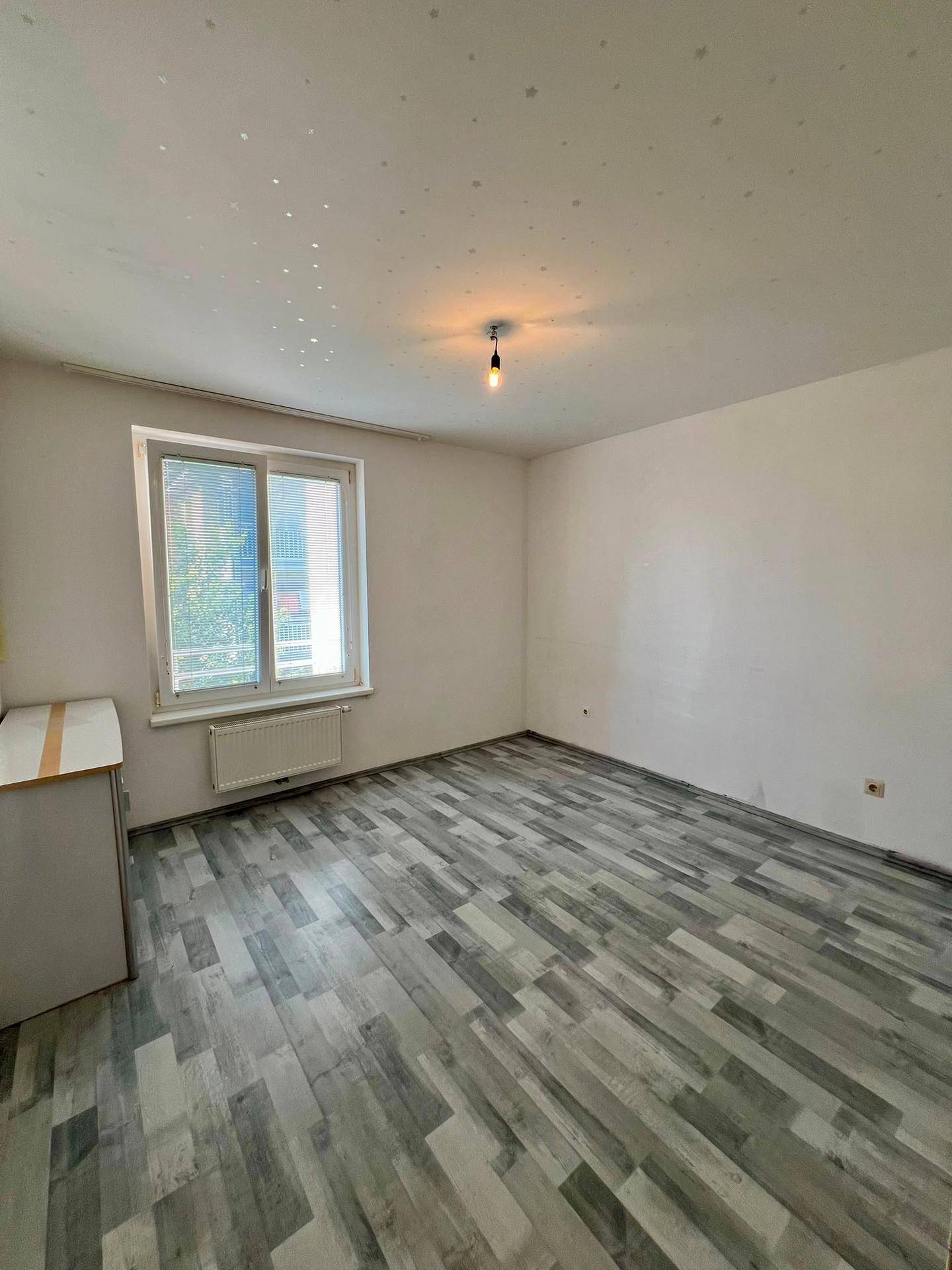 Helles Schlafzimmer mit Laminatboden und großem Fenster, unmöbliert und bereit zur Gestaltung.