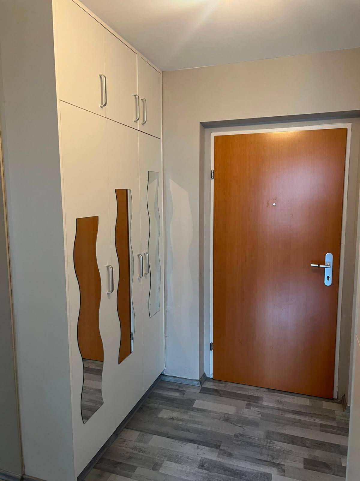 Eingangsbereich mit Laminatboden, Einbauschränken und dekorativen Spiegelelementen an der Wand.