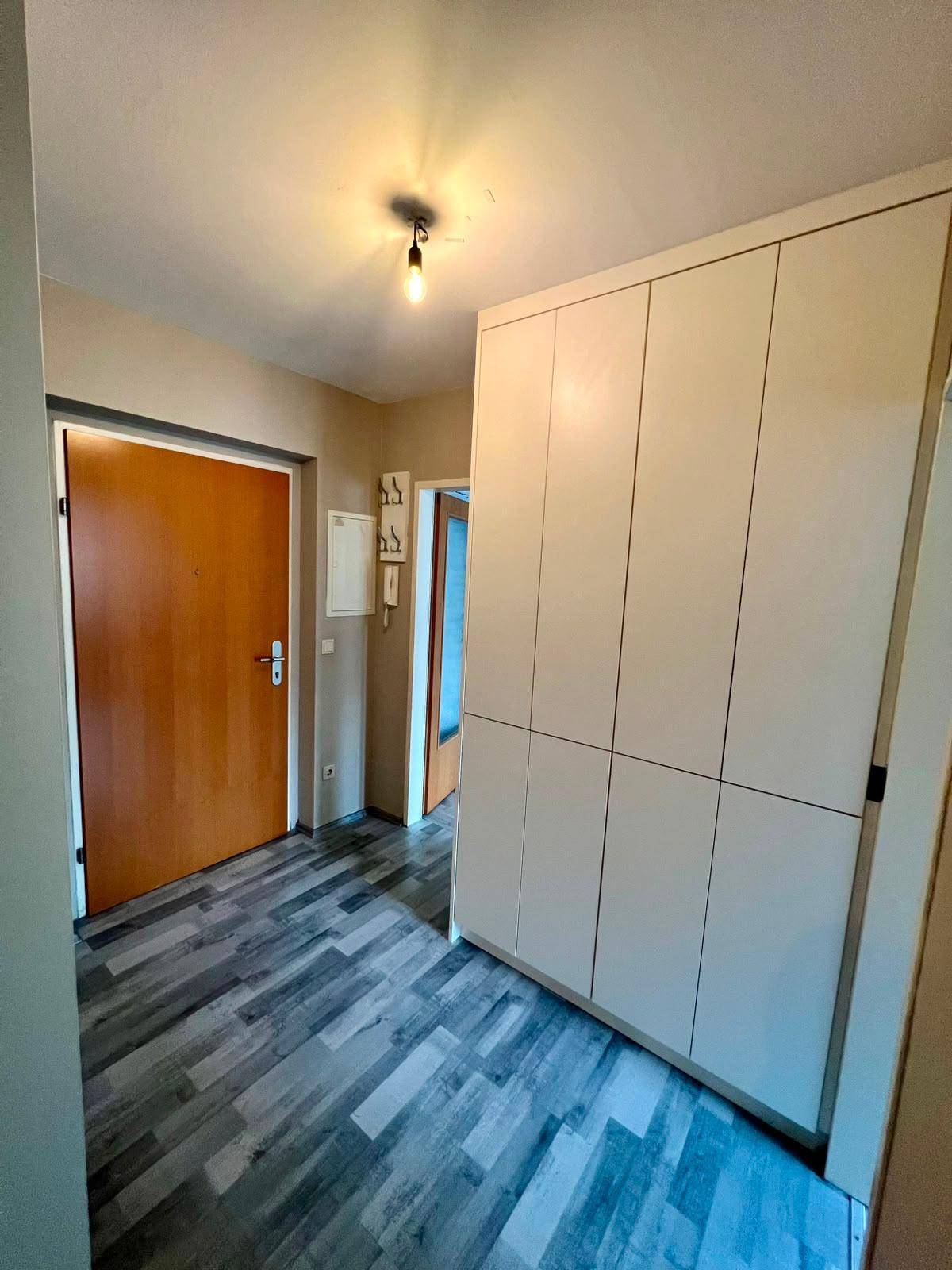 Heller Flur mit Laminatboden und praktischen Einbauschränken für zusätzlichen Stauraum.