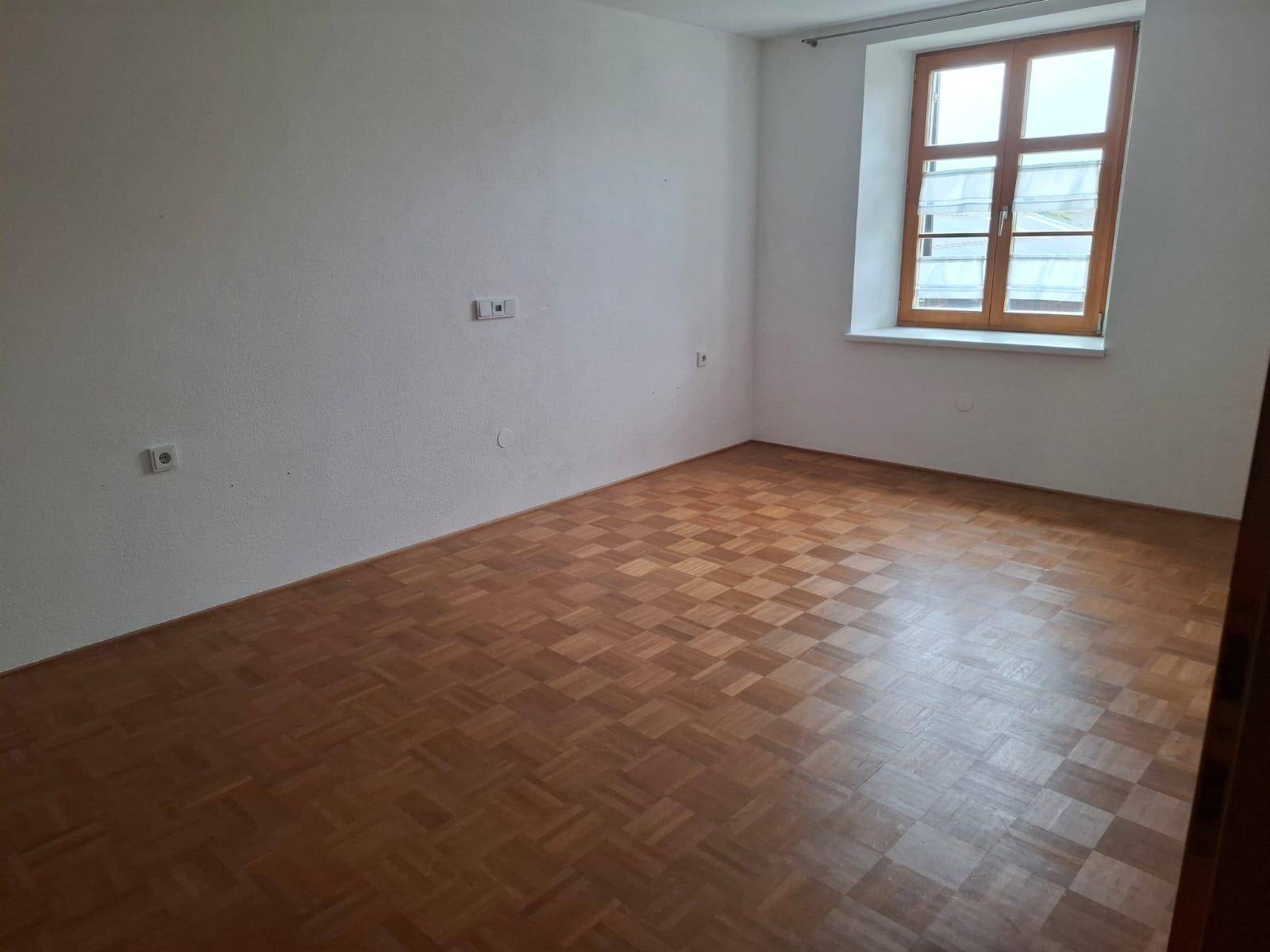 Geräumiges Zimmer mit Parkettboden und einem Fenster, das für ausreichend Tageslicht sorgt.