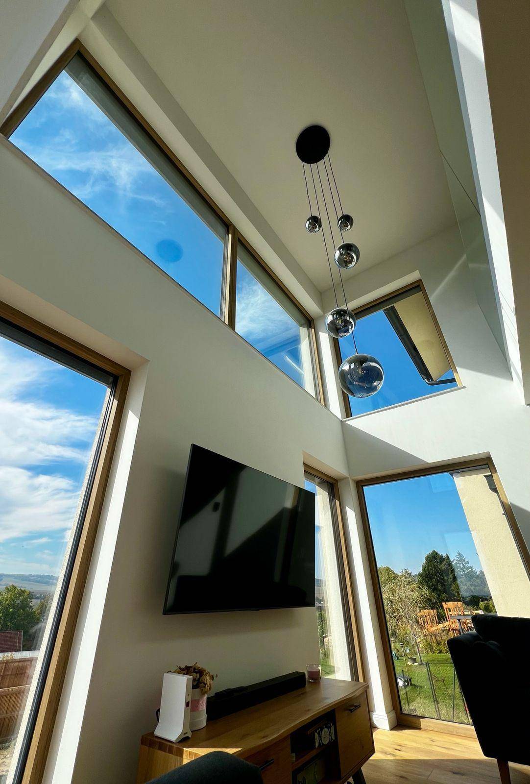 Helles Wohnzimmer mit hohen Decken, großen Fenstern und weitem Blick ins Grüne.