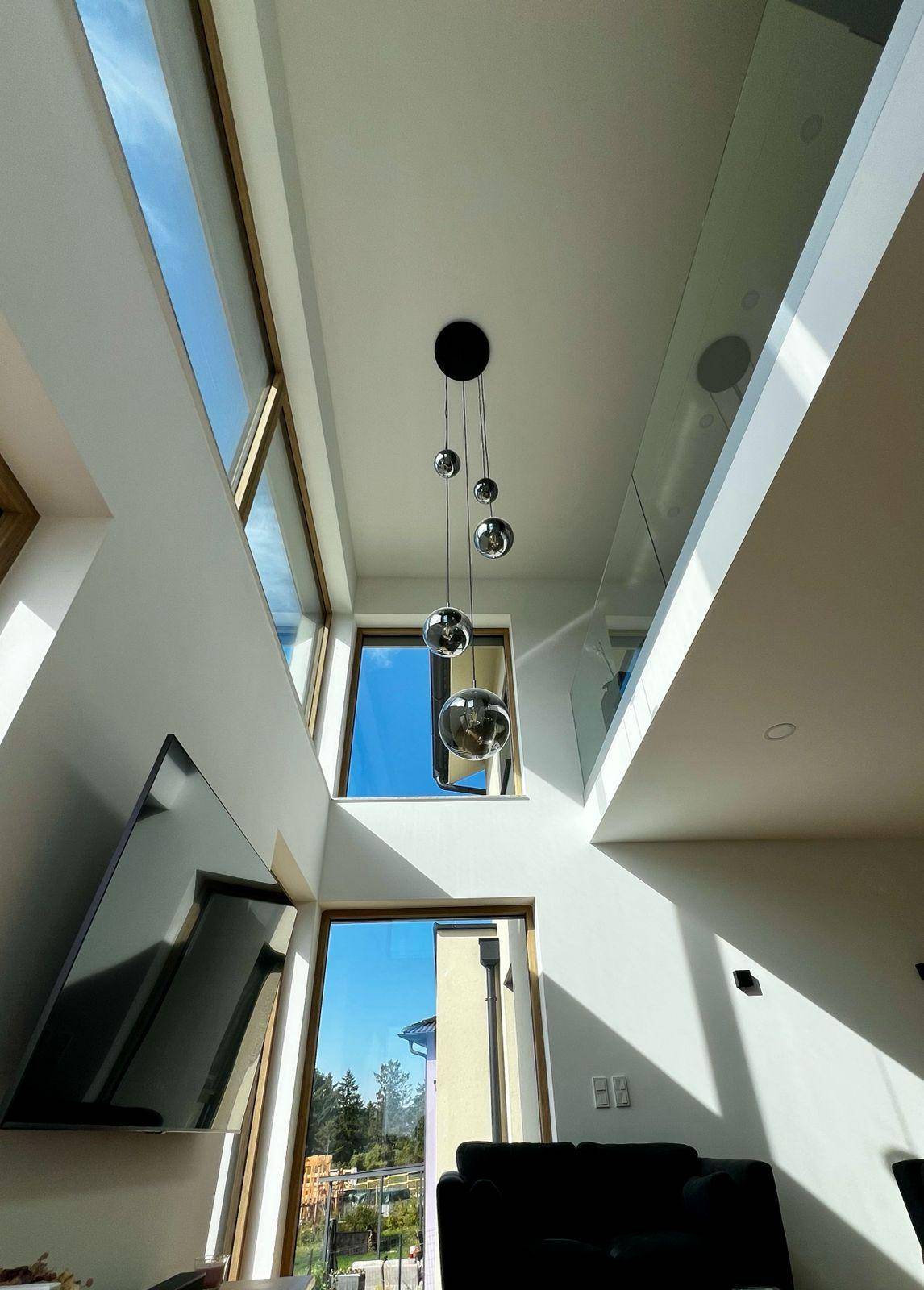 Lichtdurchfluteter Wohnbereich mit moderner Deckenleuchte und großzügigen Fensterfronten.