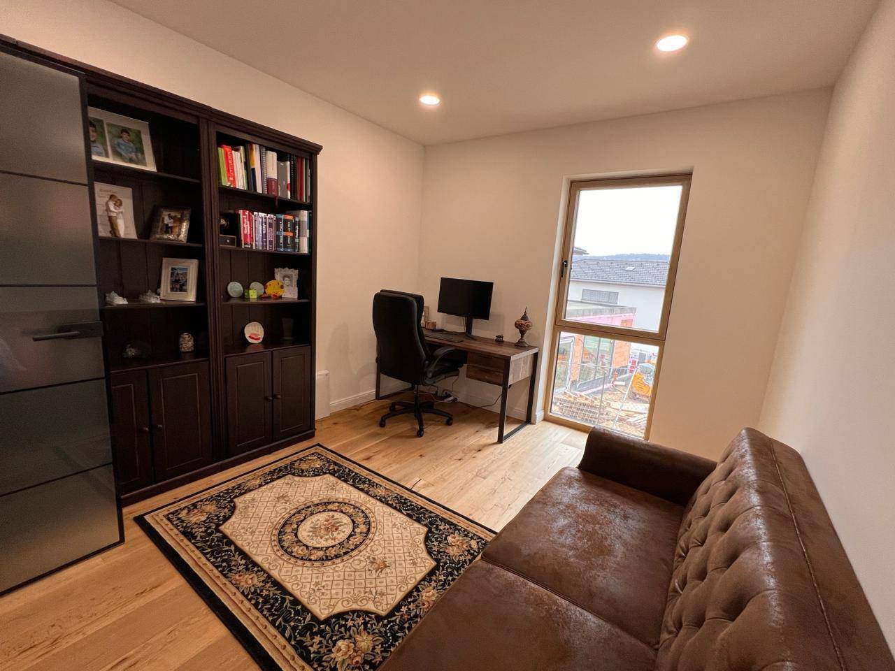 Helles Arbeitszimmer mit Holzboden, Schreibtisch und Bücherregal.