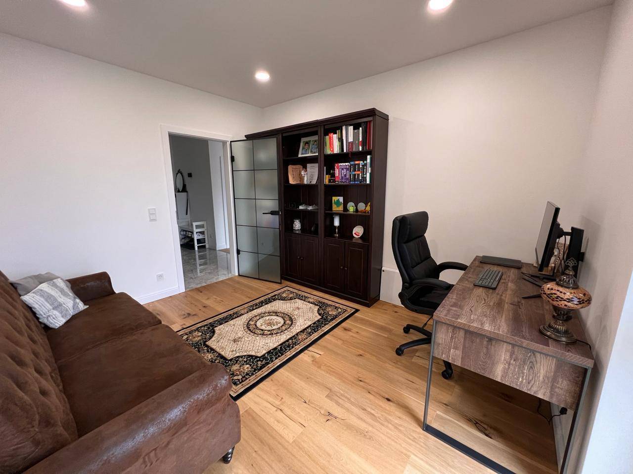 Funktionales Arbeitszimmer mit bequemer Couch, Schreibtisch und viel Stauraum.