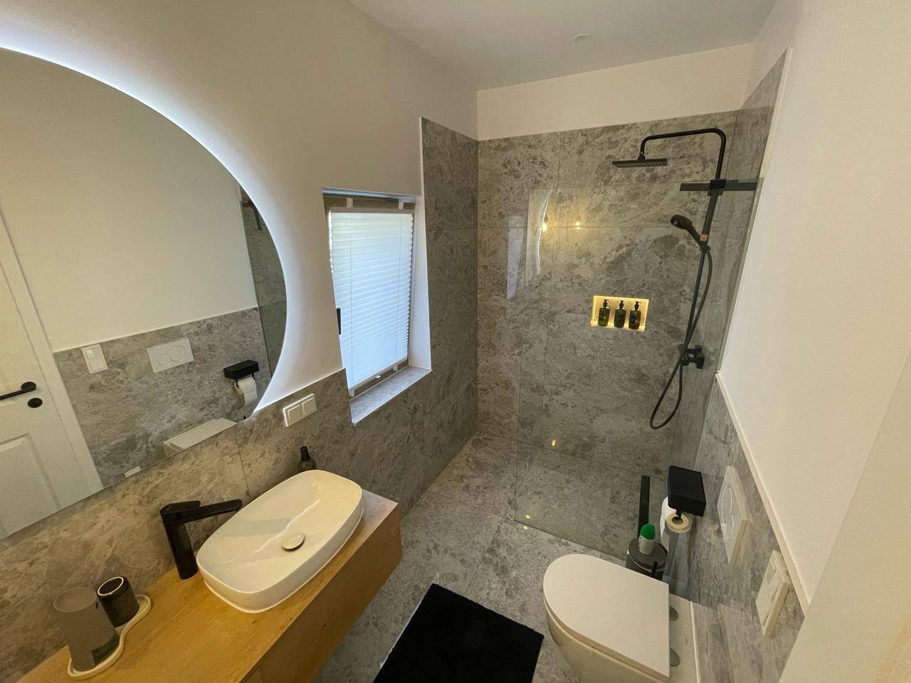 Modernes Badezimmer mit begehbarer Dusche, stilvollem Waschtisch und grauen Fliesen.