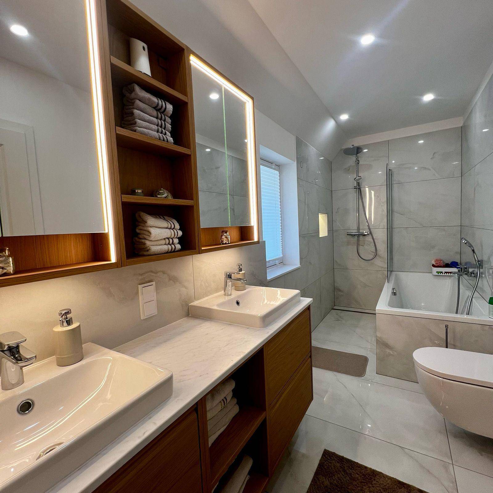 Elegantes Badezimmer mit zwei Waschbecken, Badewanne und großformatigen Fliesen.