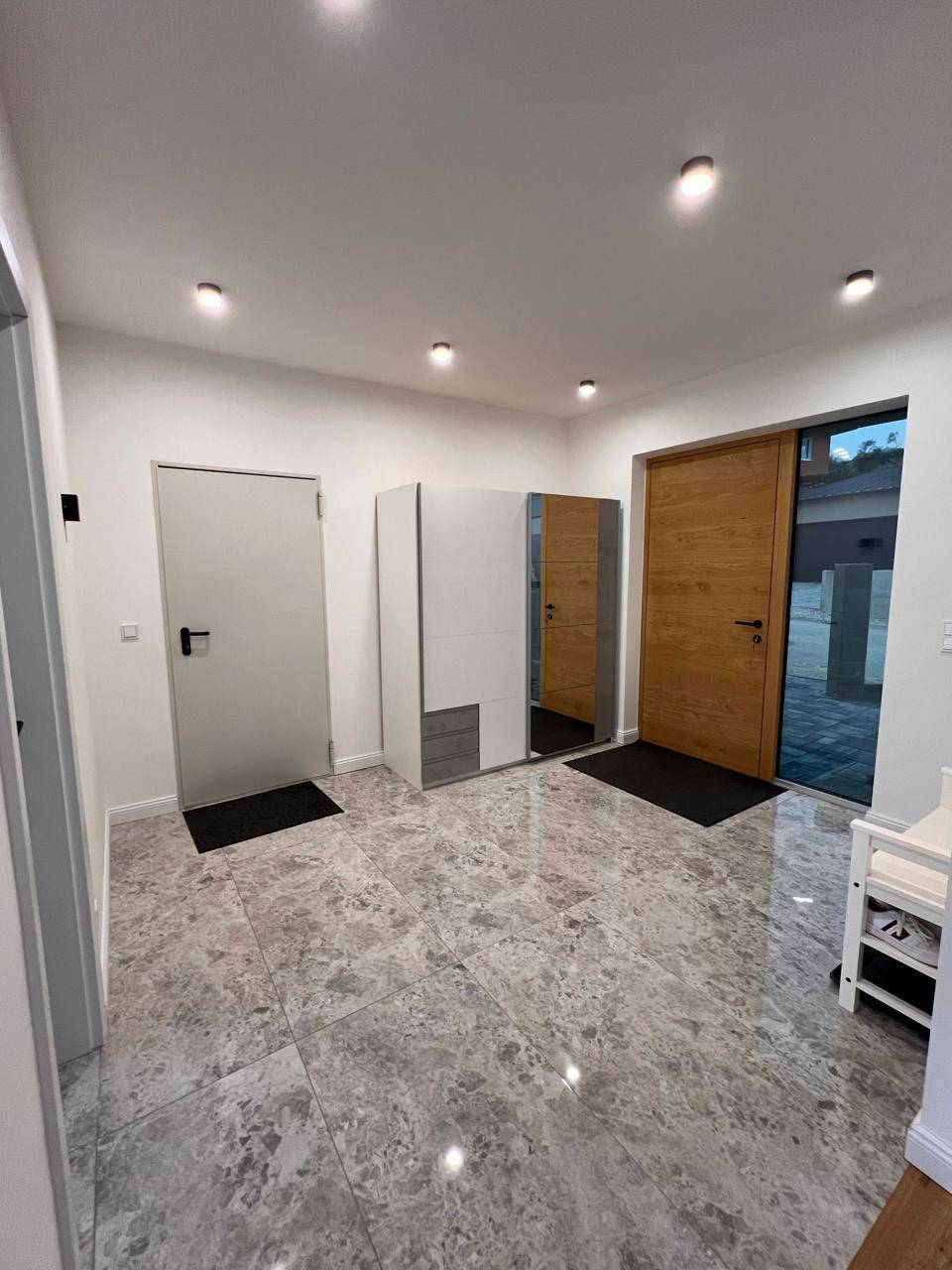 Geräumiger Eingangsbereich mit modernen Fliesen, Garderobe und Holztür.