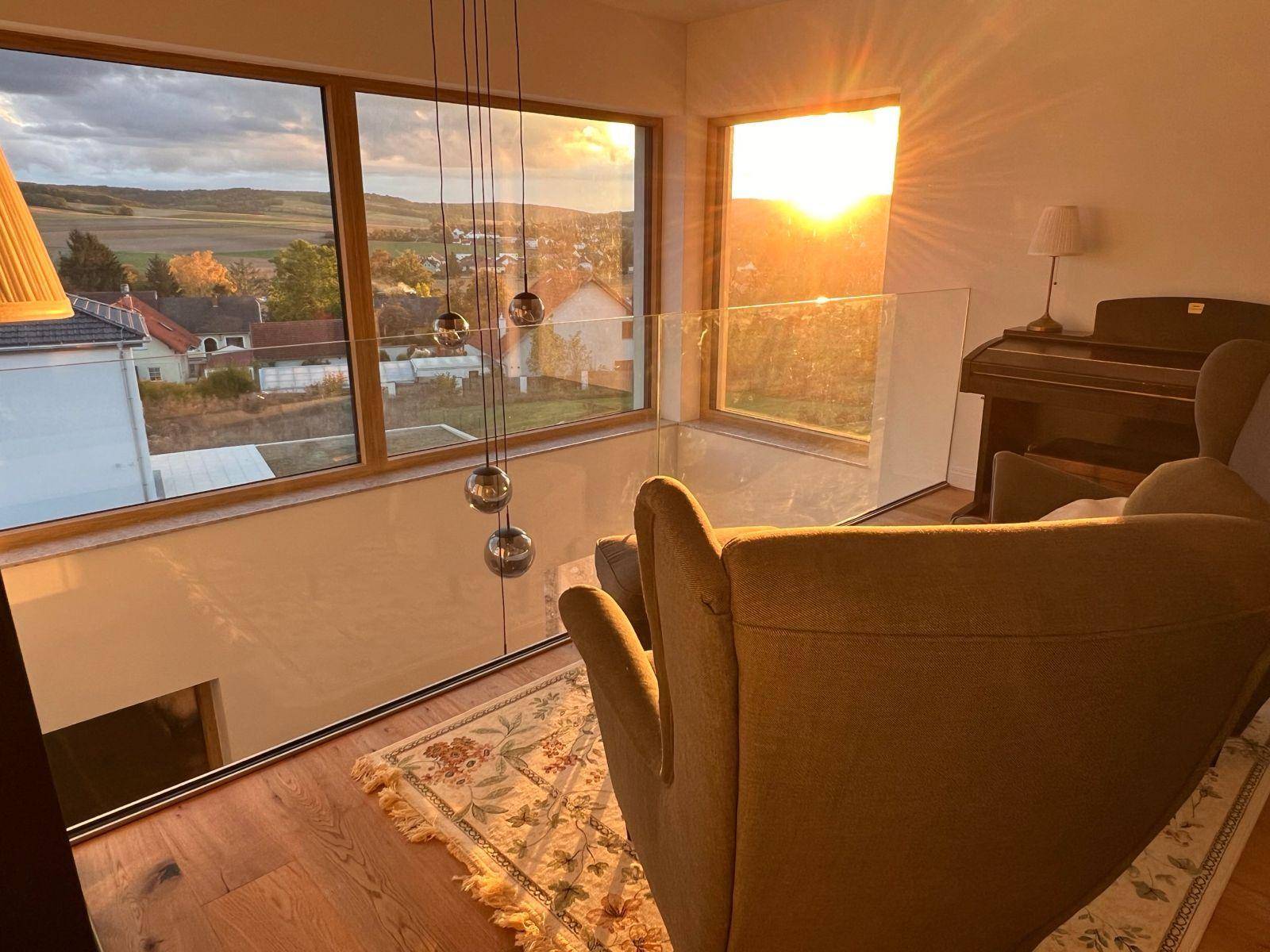 Gemütlicher Loungebereich im Obergeschoss mit weitem Ausblick und Abendsonne.