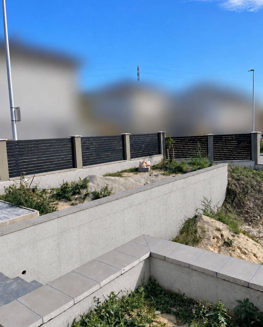 Moderne Zaunanlage mit Betonmauer und Treppen in der Außenanlage des Grundstücks.