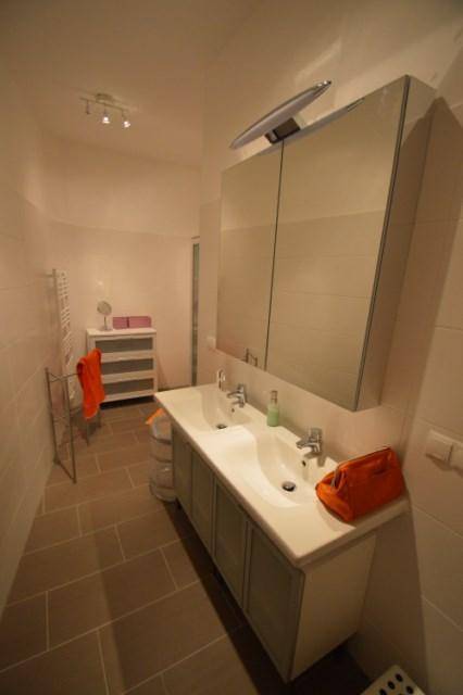 Modernes Badezimmer mit Doppelwaschbecken, Spiegelschrank und Fliesenboden für Komfort und Stil.