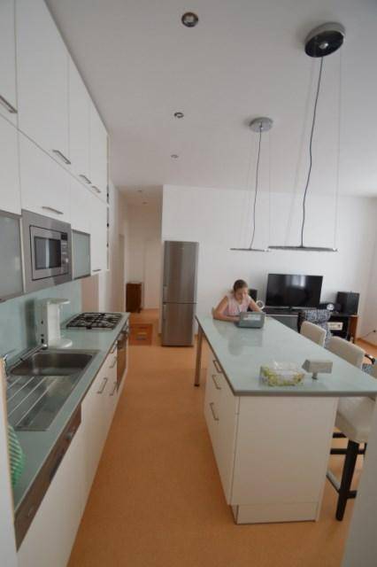 Funktionale Küche mit langer Arbeitsplatte, integrierten Geräten und Essbereich an der Kücheninsel.