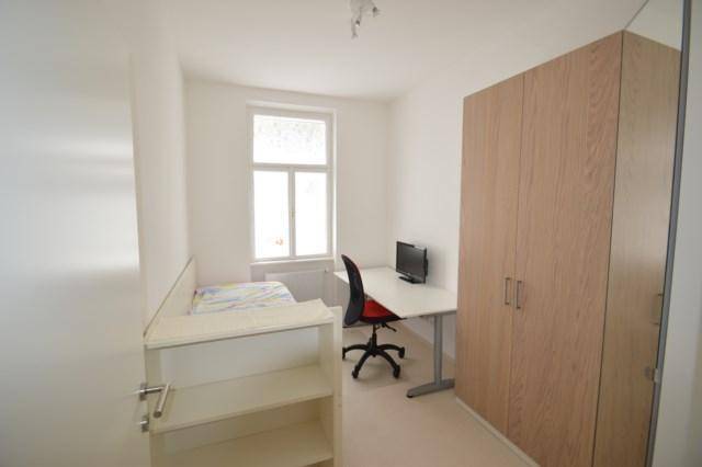 Gemütliches Schlafzimmer mit Einzelbett, Schreibtisch und hellem Holzschrank, ideal für Ruhe und Arbeit.