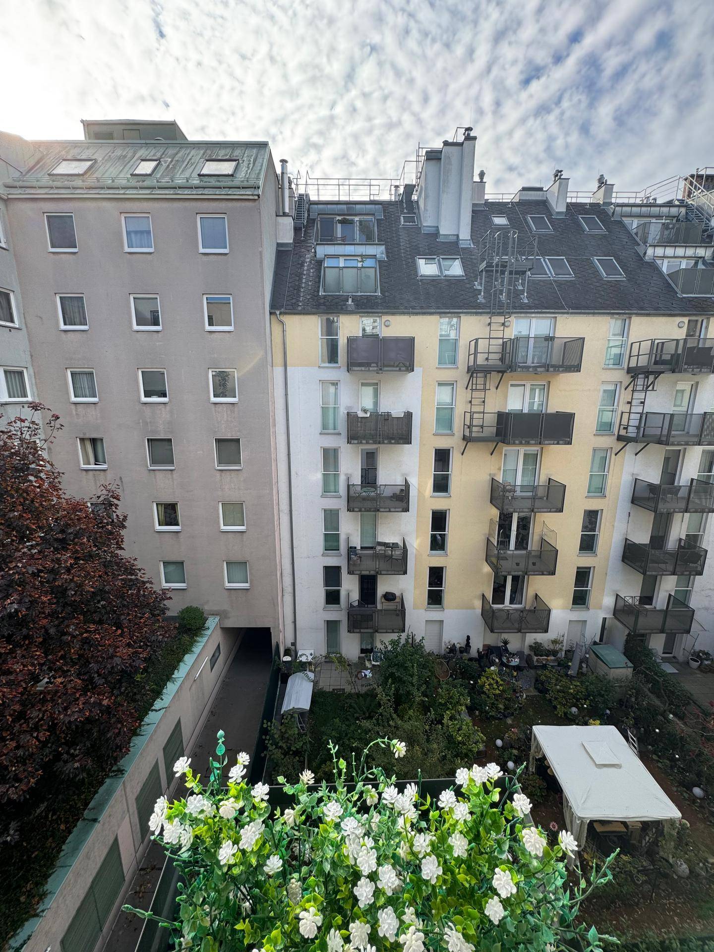Blick von oben auf die Rückseite eines Wohngebäudes mit mehreren Balkonen und einem begrünten Innenhof.