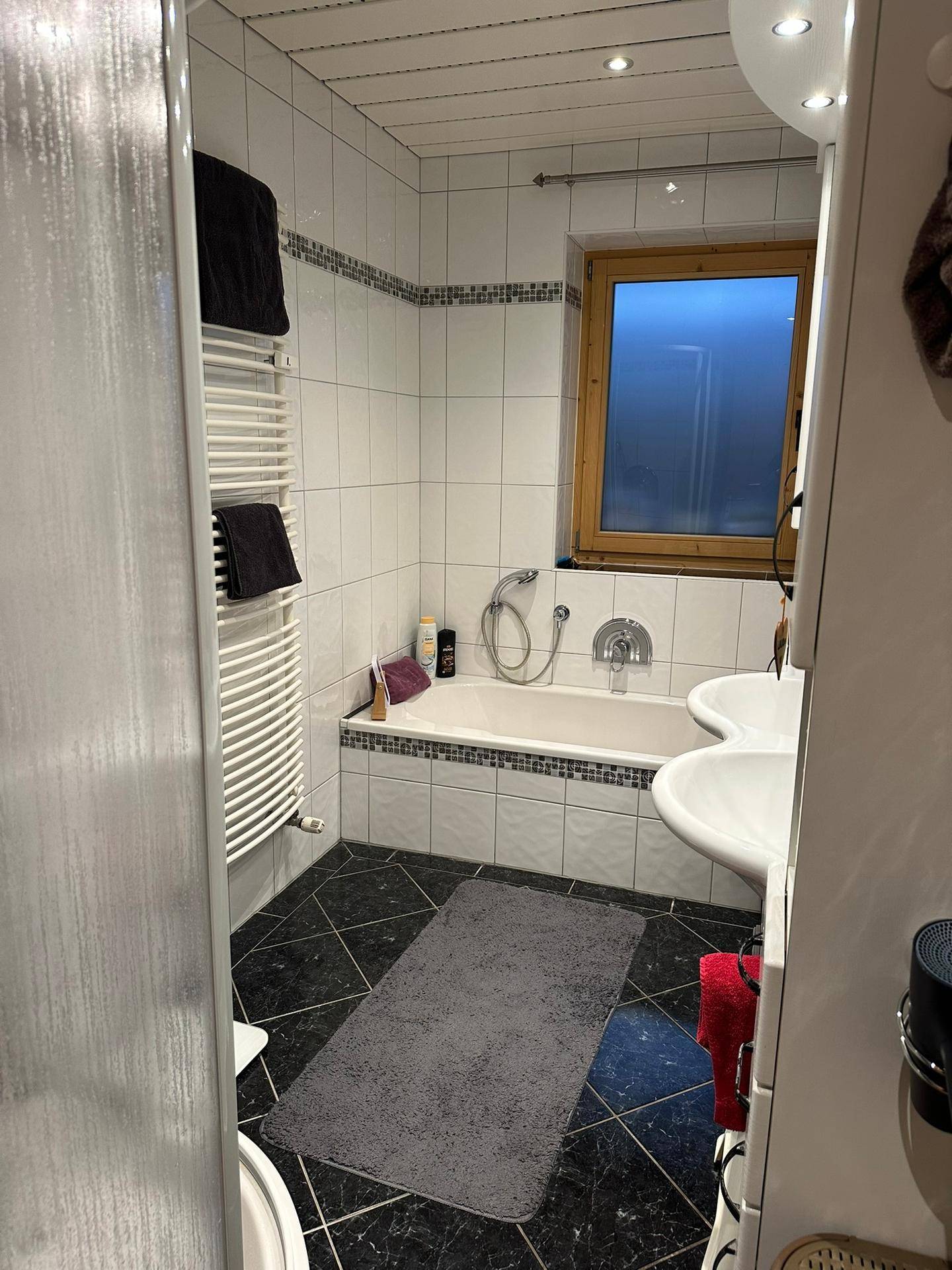 Badezimmer mit Badewanne, Doppelwaschbecken und weißen Fliesen in klassischem Design.