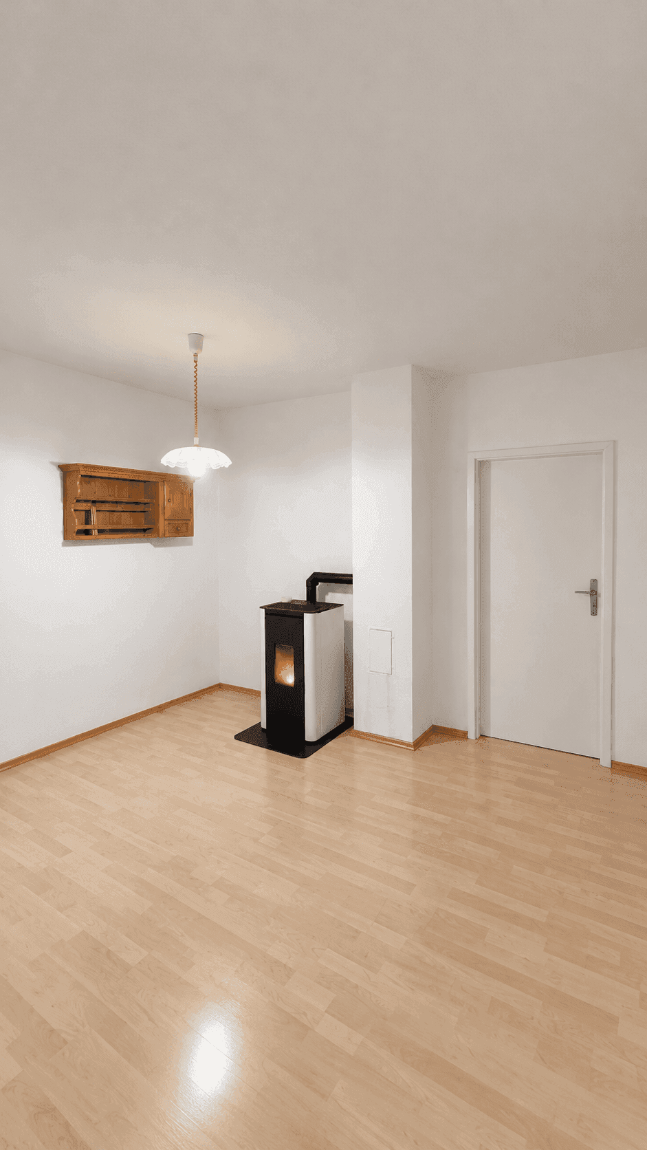 Geräumiger, heller Raum mit Laminatboden und einem modernen Holzofen als Wärmequelle.