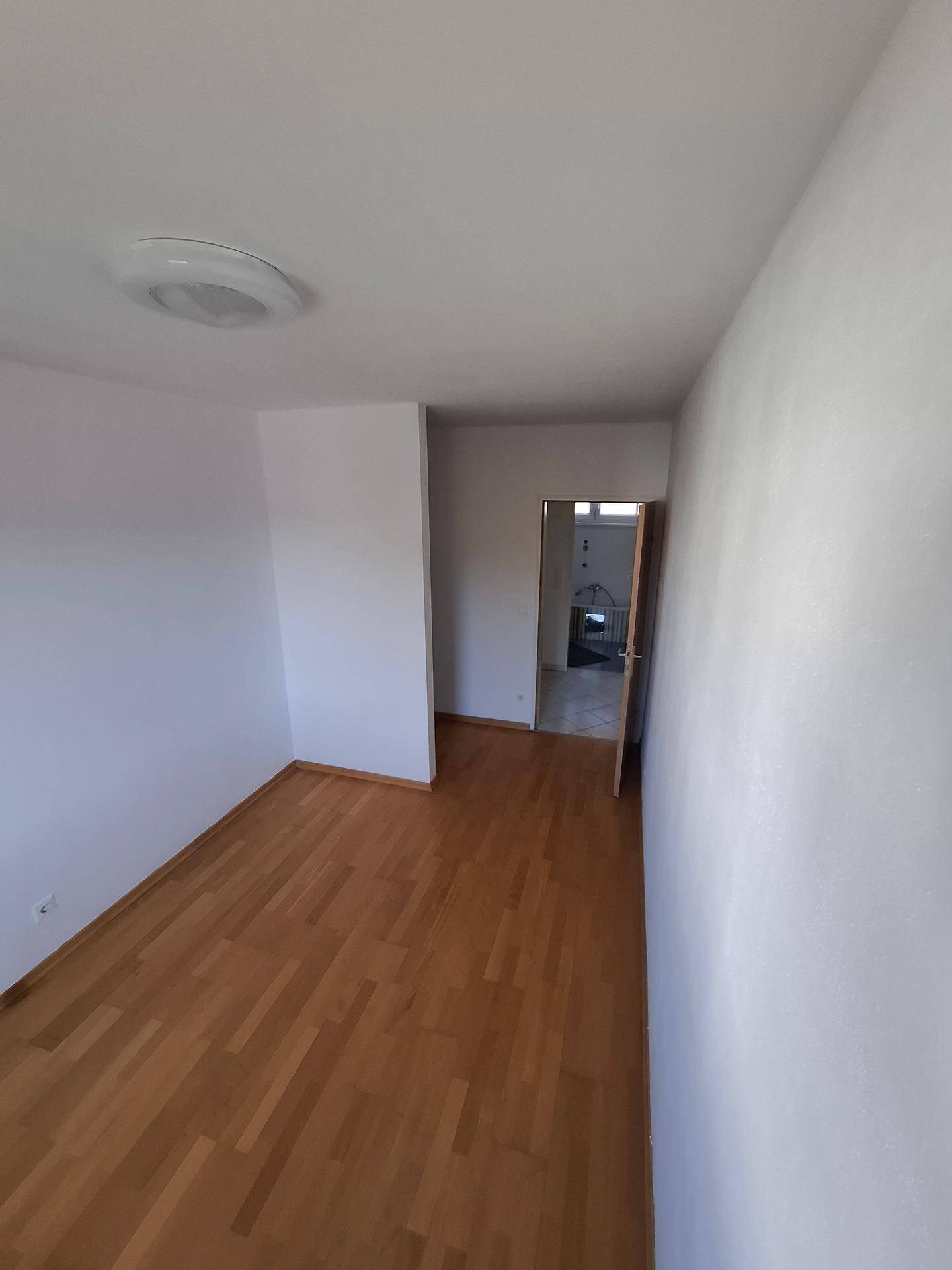 Leeres Zimmer mit Holzboden und weißen Wänden, bereit zur individuellen Gestaltung.