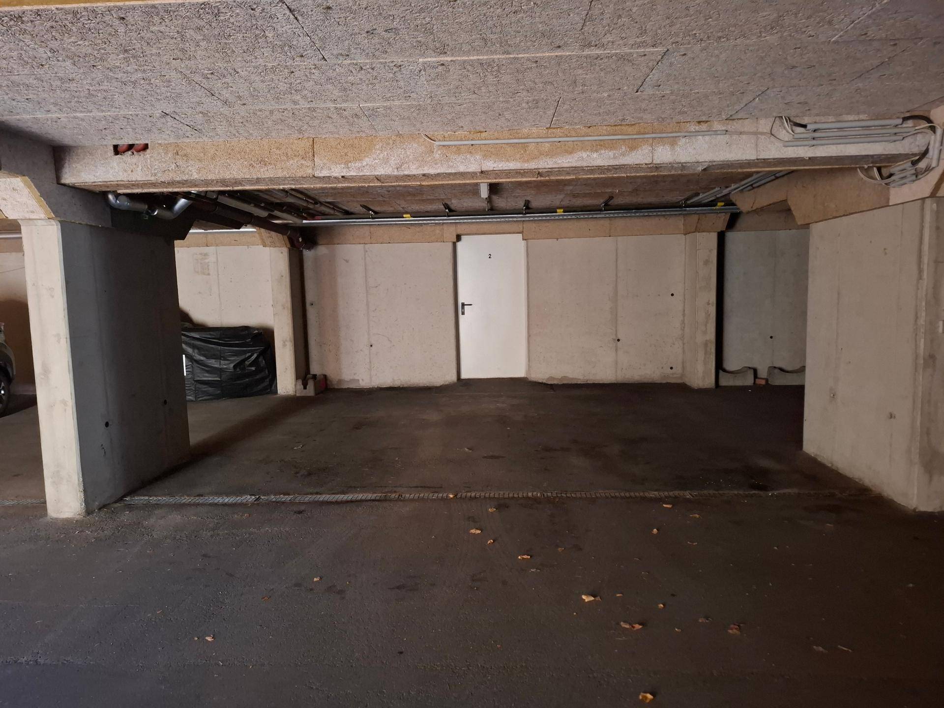 Tiefgarage mit Betonstützen und dunklem Boden, bietet sichere Parkmöglichkeiten.