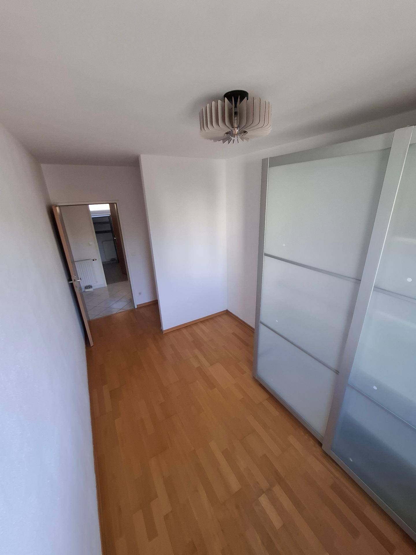 Weiterer Blick in das Schlafzimmer mit Holzboden und einem modernen Einbauschrank mit Schiebetüren.