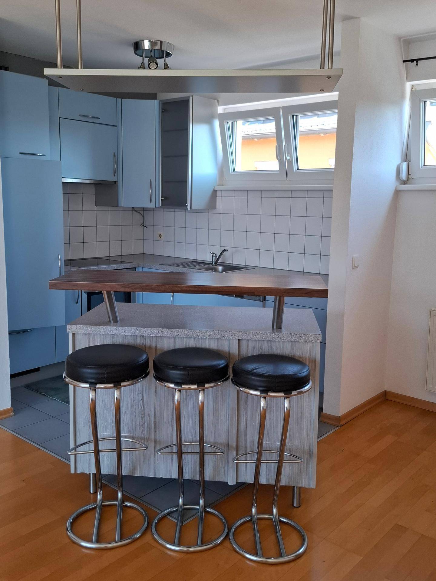 Funktionale Küche mit hellblauen Schränken, weiß gefliestem Spritzschutz und einer praktischen Frühstücksbar.