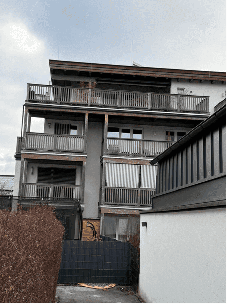 Ansicht eines modernen Mehrfamilienhauses mit mehreren Balkonen und Holzgeländern.