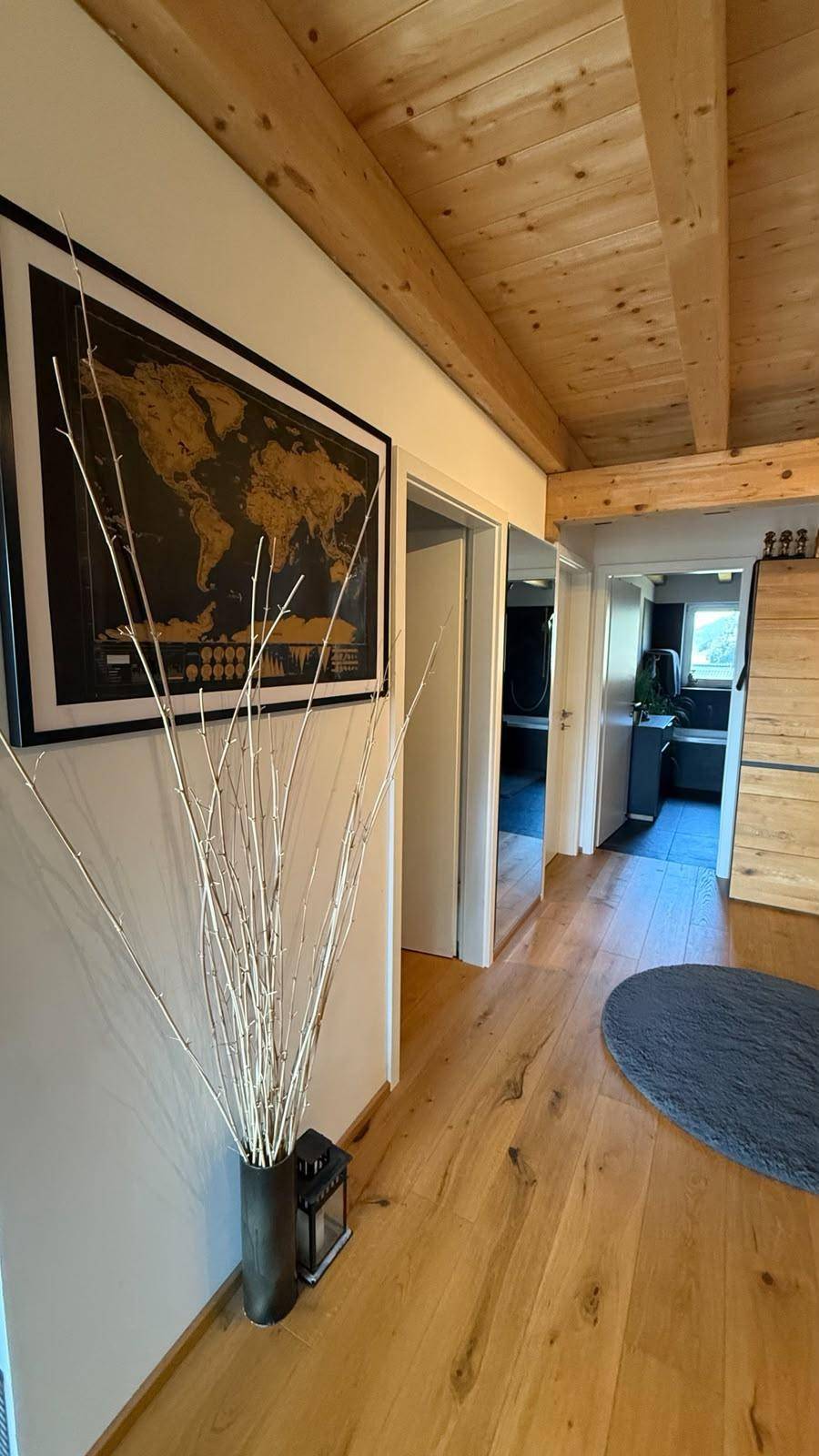 Heller Flur mit Holzboden, Holzbalkendecke und dekorativer Weltkarte an der Wand.