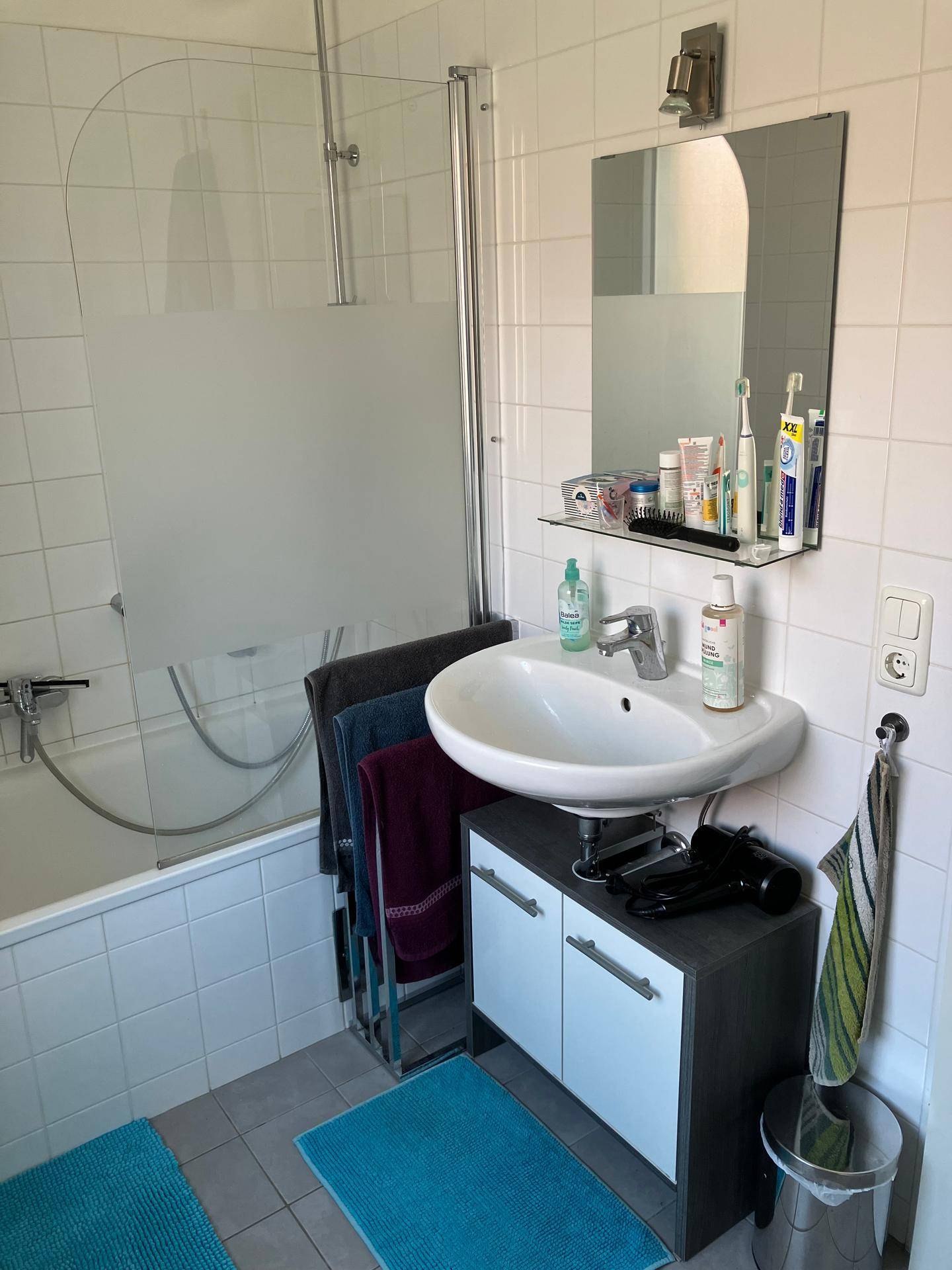 Modernes Badezimmer mit Badewanne, Duschabtrennung, Waschbecken und weißen Fliesen.