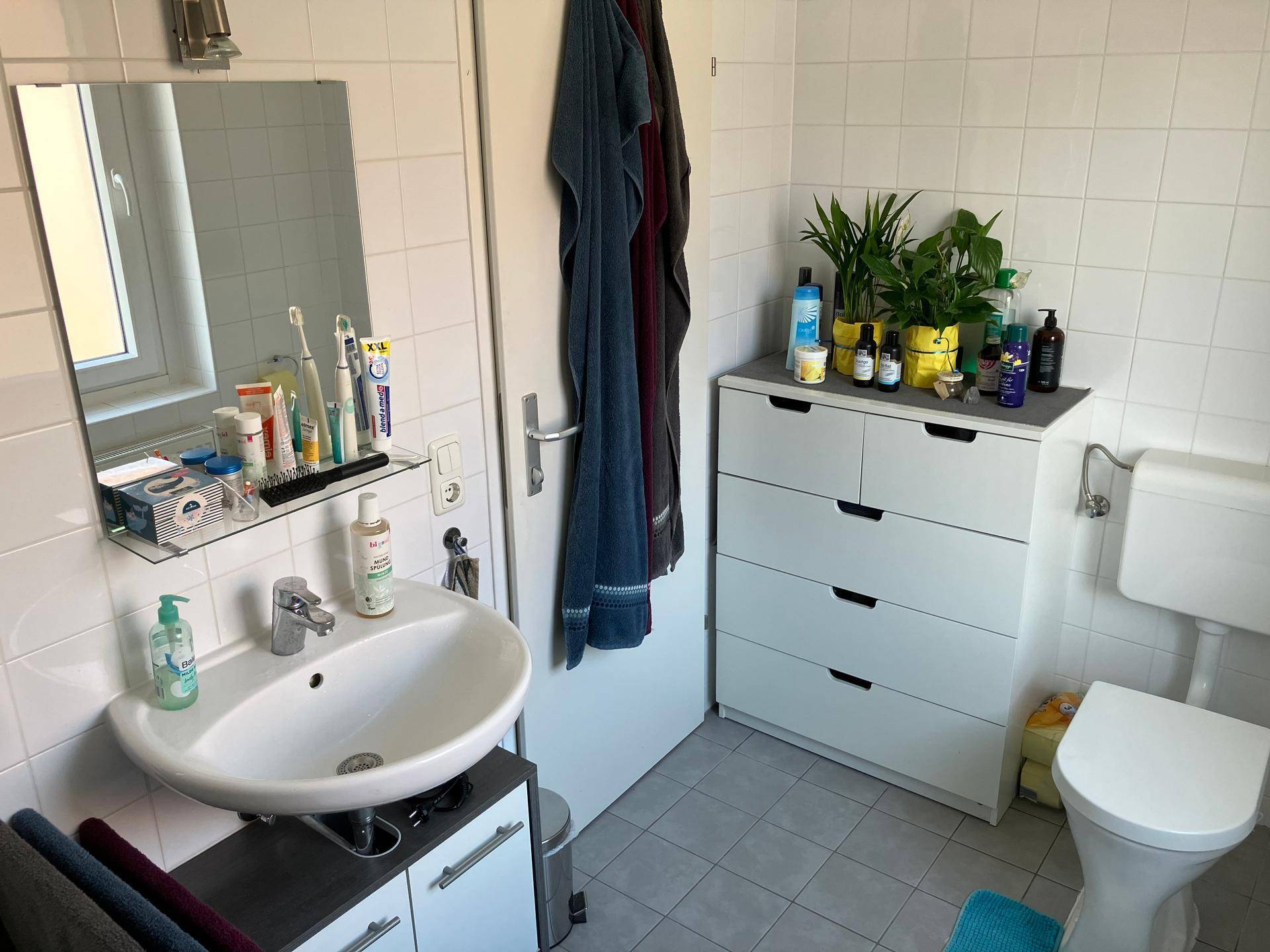 Helles Badezimmer mit WC, Waschbecken und Fenster, das für natürliche Belüftung sorgt.