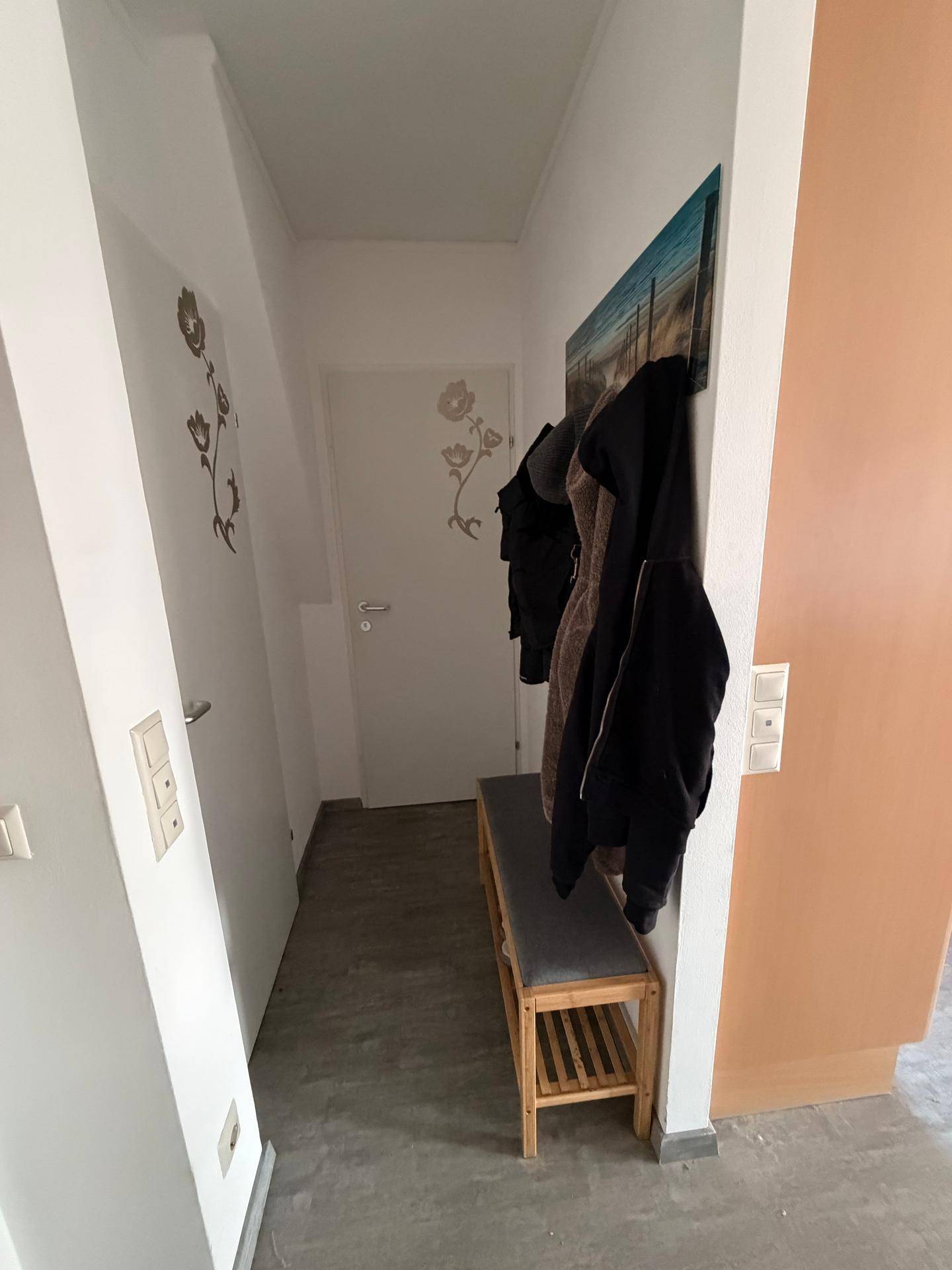 Heller Eingangsbereich mit Garderobe und einer kleinen Sitzbank, ideal für den Empfang von Gästen.