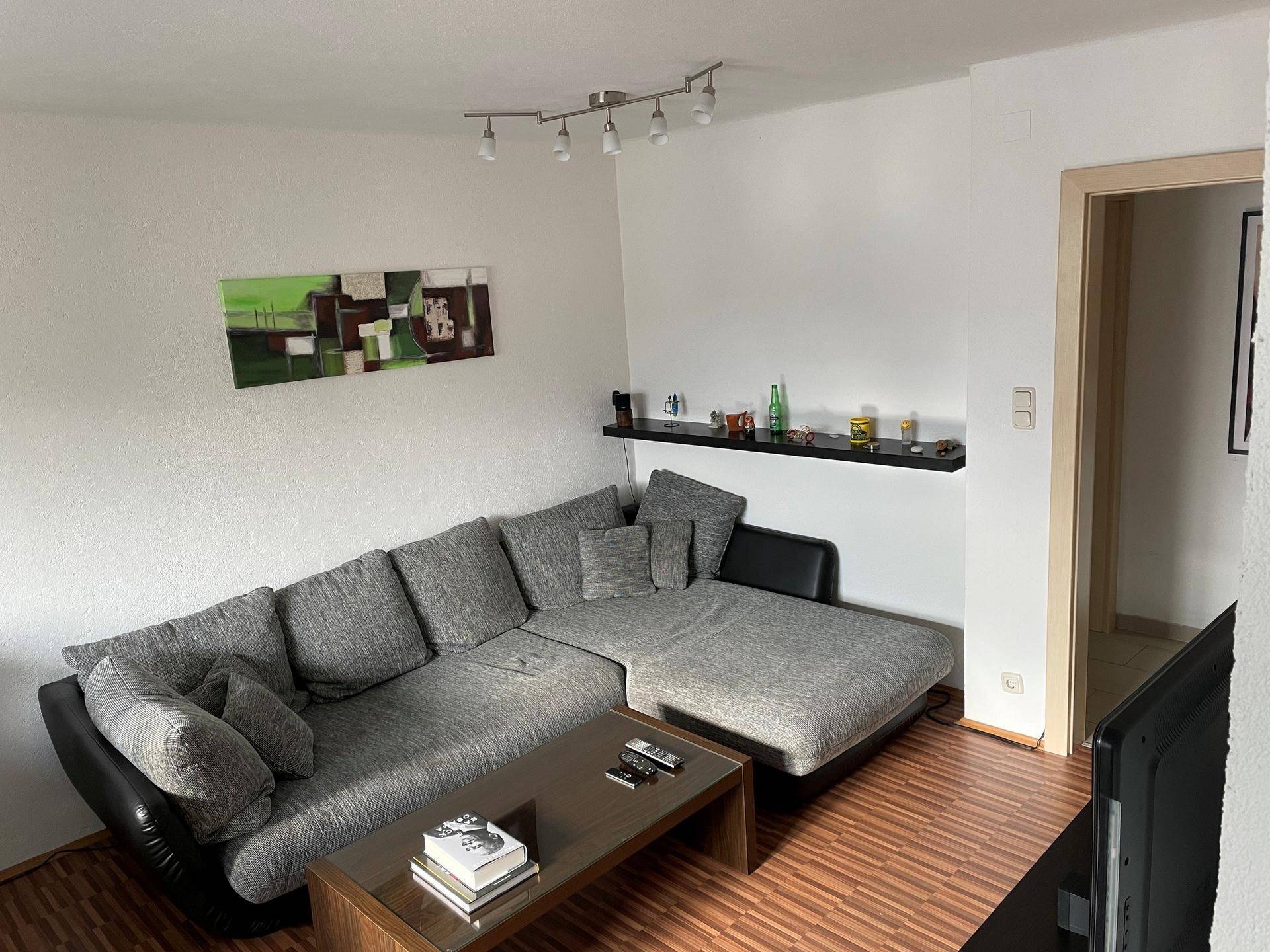 Heller Wohnbereich mit bequemem Ecksofa und moderner Wanddekoration, bietet viel Platz zum Entspannen.