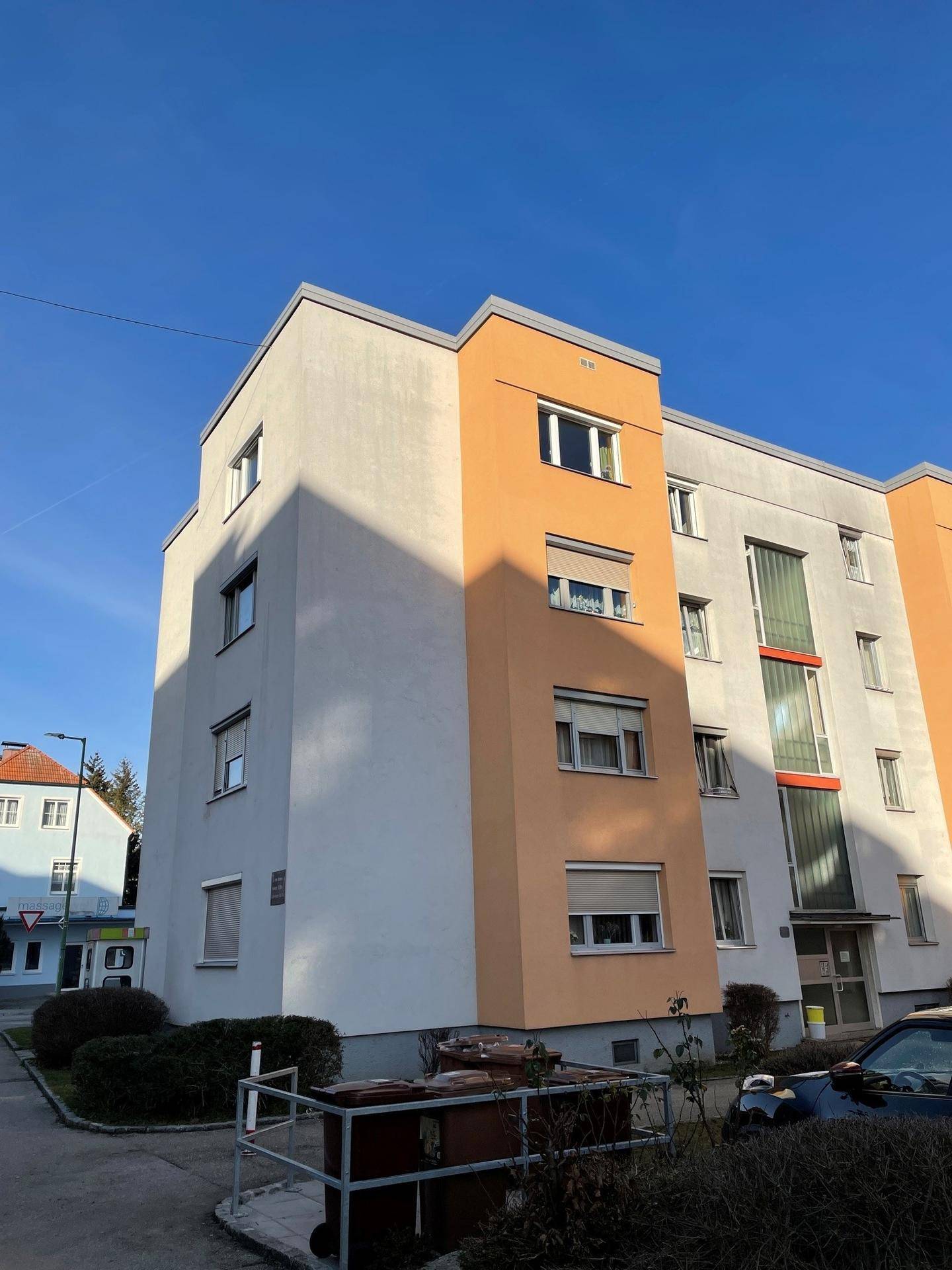 Modernes Mehrfamilienhaus mit farbigen Akzenten und klaren Linien unter blauem Himmel.