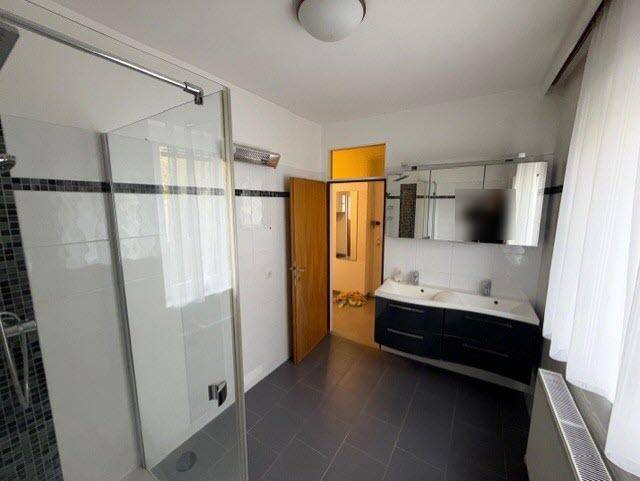 Badezimmer mit Doppelwaschbecken, Dusche und Fenster, hell und funktional, mit Spiegelschrank.